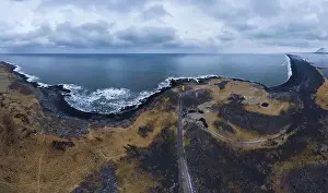 Navigate Prints: Aerial view of small orange lighthouse placed near asphalt road in coastal area against blue sea in Iceland