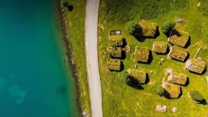 Aerial view of a small village in Norway with traditional grass-covered rooftops nestled amongst green fields