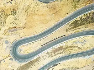Top aerial view of snake curved road. Winding mountains road. View from above. Driveway serpentine with cars