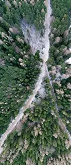Aerial view of snowy winter forest with a road in austria