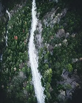 Aerial view of snowy winter forest with a road in austria