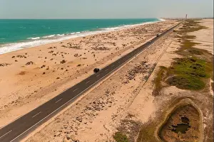 Tamil Nadu Prints: Aerial view of a stark road cutting through the sandy landscape where the turquoise ocean meets the shore