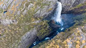 Vale Prints: Aerial view of a stunning waterfall cascading down rocky cliffs into a deep blue pool surrounded by lush greenery
