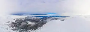 Hill Glacier Prints: Aerial view of the stunning winter panorama of the snowy slopes and hills among the lush white clouds