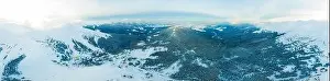 Aerial view of the stunning winter panorama of the snowy slopes and hills among the lush white clouds