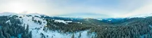Aerial view of the stunning winter panorama of the snowy slopes and hills among the lush white clouds