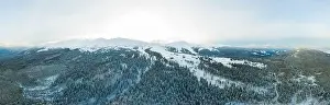 Aerial view of the stunning winter panorama of the snowy slopes and hills among the lush white clouds
