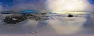 Aerial view of the stunning winter panorama of the snowy slopes and hills among the lush white clouds
