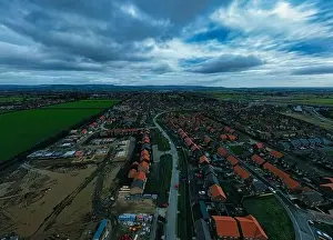 Aerial view of a suburban neighborhood with rows of houses under a dramatic cloudy sky