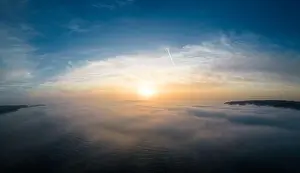 Aerial view of a sunrise sea with a blanket of morning fog and morning sunbeams shining through