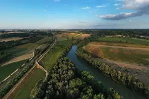 Aerial view of Tanaro river, vegetation and cultivated fields during a sunny afternoon in summer