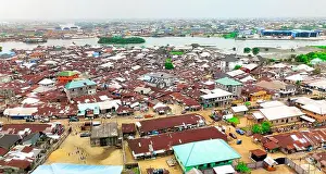 Nigeria Prints: Aerial view of tightly packed buildings with corrugated iron roofs meeting the waterways