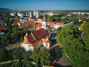 Bird Eye View Prints: Aerial view of the towering church with its red roof and steeple rises amidst the verdant embrace of trees