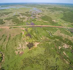 Nature Tourism Prints: Aerial view of Transpantaneira dirt road crossing a lagoon over a small bridge in the typical landsc