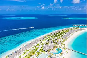 Aerial view of a tropical island in turquoise water. Luxurious over water villas on tropical island resort. Maldives aerial landscape holiday vacation