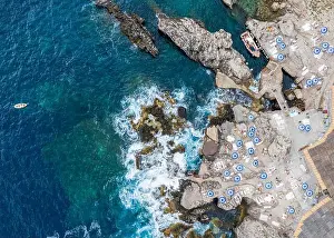 Sunbathers Prints: Aerial view of turquoise waters crashing against rugged cliffs