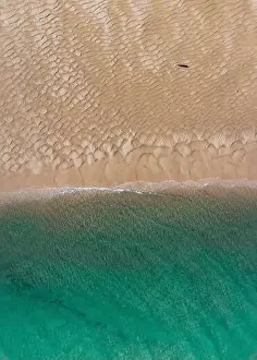 Seawater Prints: Aerial top view of unrecognizable traveler walking along turquoise ocean washing sandy beach with rippled sand on sunny