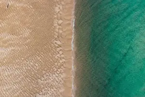 Huelva Prints: Aerial top view of unrecognizable traveler walking along turquoise ocean washing sandy beach with rippled sand on sunny