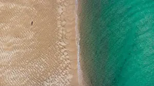 Seawater Prints: Aerial top view of unrecognizable traveler walking along turquoise ocean washing sandy beach with rippled sand on sunny