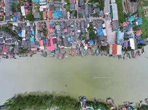 Speedboat Prints: Aerial view top view of the fisherman village with fishing boats and house roof at the pier in suratthani Thailand