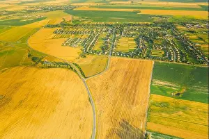 Aerial View Of Village And Hay Rolls, Straw Field Landscape In Summer Evening. Haystack, Hay Roll in Sunrise Time. Agricultural Countryside landscape