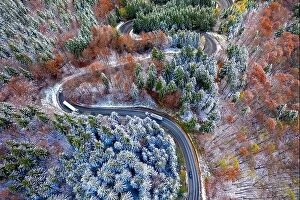Images Dated 1st November 2019: Aerial view of a winding mountain road passing through a fir trees forest. Winter with snow