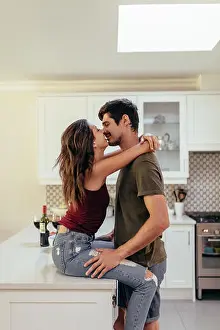 Flirting Prints: Affectionate young couple together in the kitchen at home. Couple in love kissing at home
