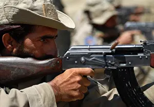 An Afghan security guard, assigned to Forward Operating Base Torkham, fires an AK-47 assault rifle during a weapons range hosted by the 527th