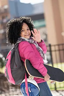 Curly Hair Prints: African American girl carrying skateboard outdoors