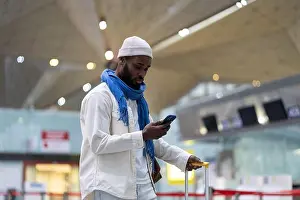 Booking Prints: African American man passenger looking at mobile boarding pass on smartphone in check-in area
