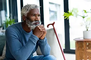 Contemplating Prints: African american senior man contemplating while sitting with hands on chin looking away at home