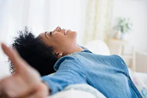 African Ethnicity Prints: African American woman with arms outstretched on sofa