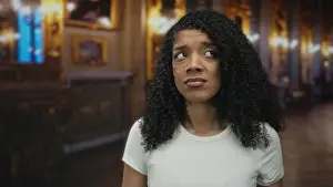 Glance Prints: African american woman in white shirt furrows brow in museum building; uncertainty doubt tension concern