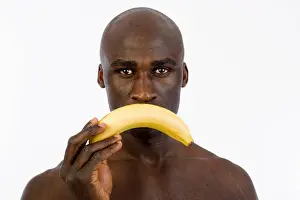 Nourishments Prints: African man holding a banana in front of his mouth
