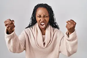 Braids Prints: African woman standing over white background angry and mad raising fists frustrated