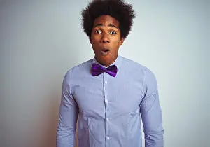 Panic Prints: Afro business man wearing striped shirt and purple bow tie over isolated white background afraid