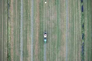 Agricultural tractor collects mowed grass for agricultural use and wraps hay bales in a plastic field, Friesland