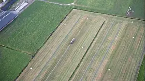 Agricultural tractor collects mowed grass for agricultural use and wraps hay bales in a plastic field, Friesland