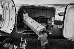 Airline workers load cargo (empty coffins) to a Douglas DC-3 aircraft at the airport of Villavicencio, Colombia