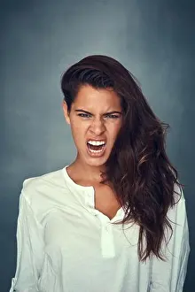 Pulling Prints: Get it all off your chest. Portrait of a beautiful young woman pulling a funny face against a gray background in studio