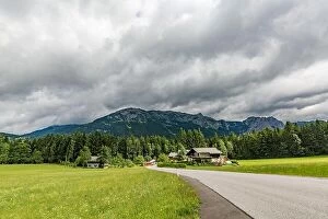 Images Dated 25th July 2017: Alps in Austria. Wooden house before mountains green field and road through green pine forest