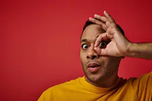 Expressing Positivity Prints: amazed indian man in yellow t-shirt showing okay sign, hand near face background in studio