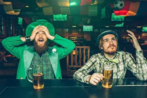 Intense Prints: Amazed and upset young men sit at bar counter in pub