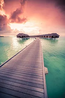 Amazing abstract background. Beautiful sunset colors in Maldives. Long jetty and luxury overwater villas