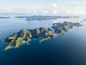 Amazing limestone islands rise from the calm seascape around Misool, Raja Ampat, Indonesia. This tropical region harbors amazing marine biodiversity