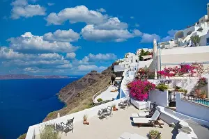 Amazing panoramic landscape, luxury travel vacation. Oia town on Santorini island, Greece. Traditional and famous white architecture and pink flowers