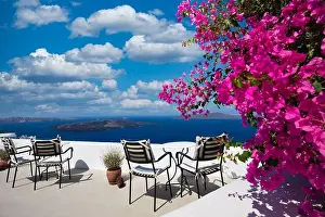 Amazing panoramic landscape, luxury travel vacation. Oia town on Santorini island, Greece. Traditional and famous white architecture and pink flowers