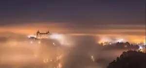 Alcazar Prints: Amazing scenery of shining and luminous ancient Alcazar de Toledo castle over town in misty twilight