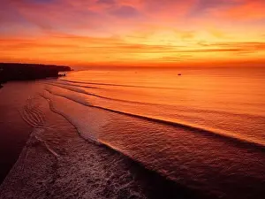 Amazing warm sunset or sunrise and ocean with silhouette of perfect waves in Bali