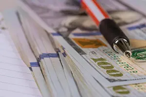 Salary Prints: One hundred american dollars banknotes and pen lying close up